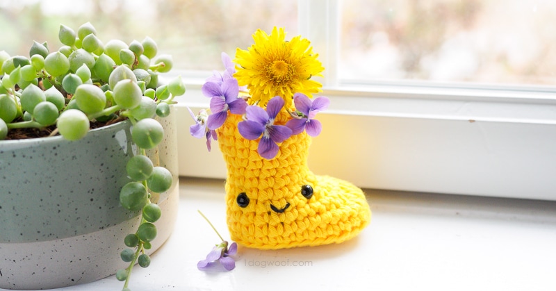 黄钩针雨鞋与紫色的花朵，坐在窗台