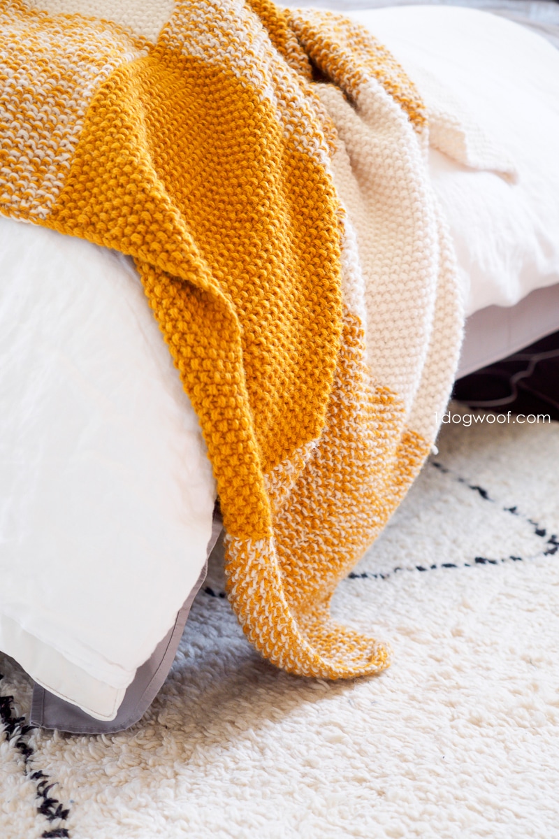 seed stitch knitted blanket draped over bed